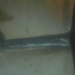 Szlif spoiny na wewnętrznym narożniku konstrukcji stalowej, widoczne ślady obróbki i niedoskonałości powierzchni.