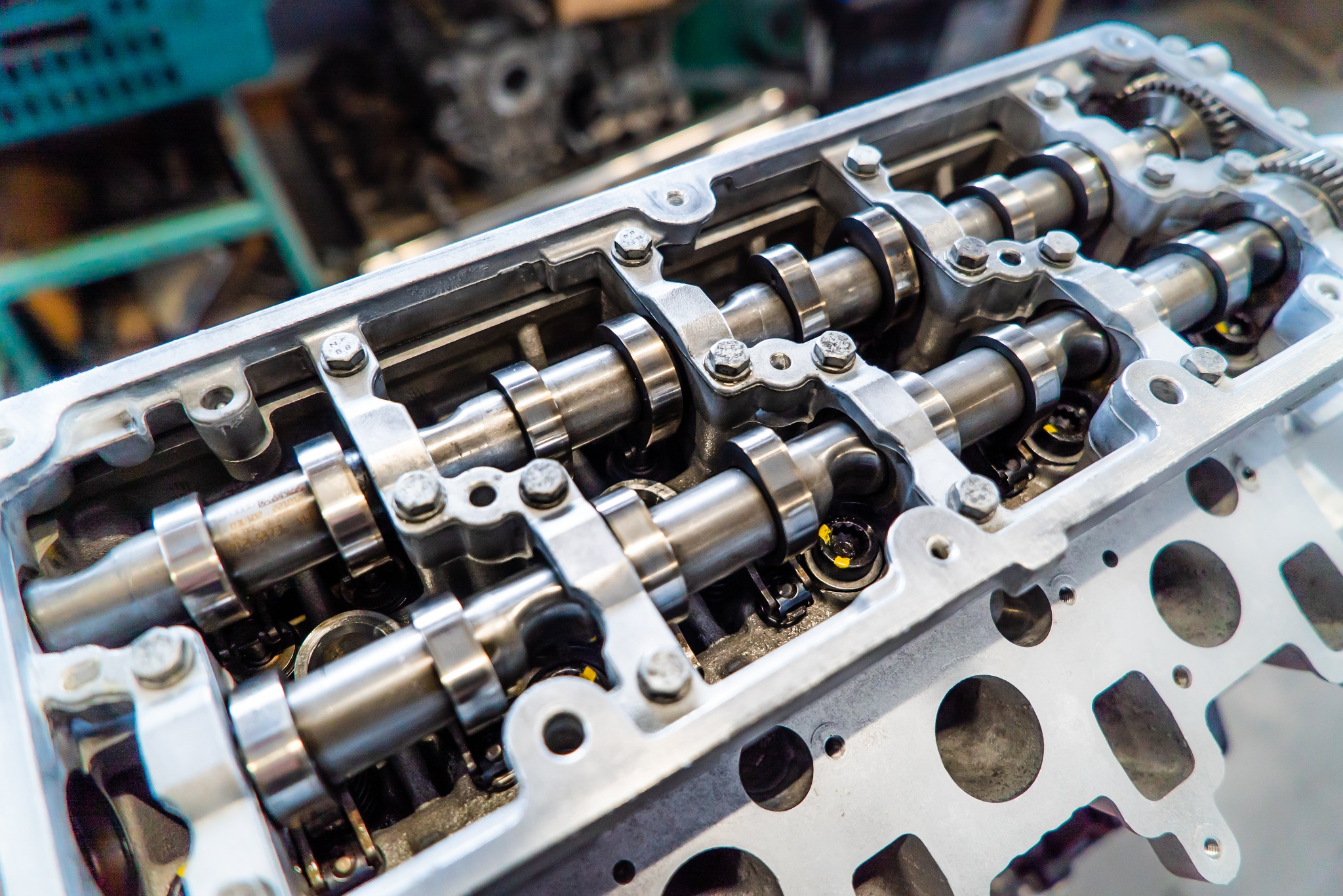 Głowica silnika samochodowego z wałkami rozrządu i zaworami, widoczne detale konstrukcyjne i ślady montażu.