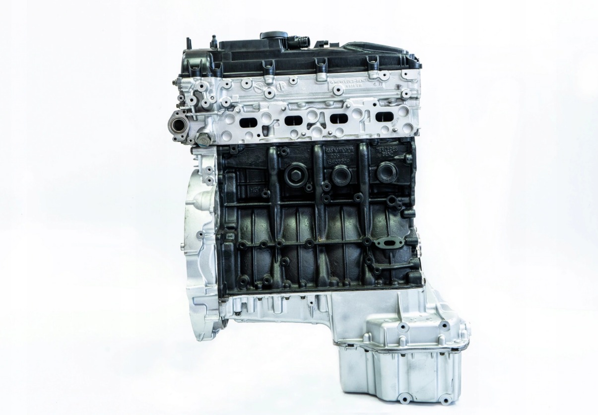 Silnik samochodowy po regeneracji, z czarnym blokiem i srebrną głowicą, widoczne oznaczenia Mercedes-Benz, na białym tle.
