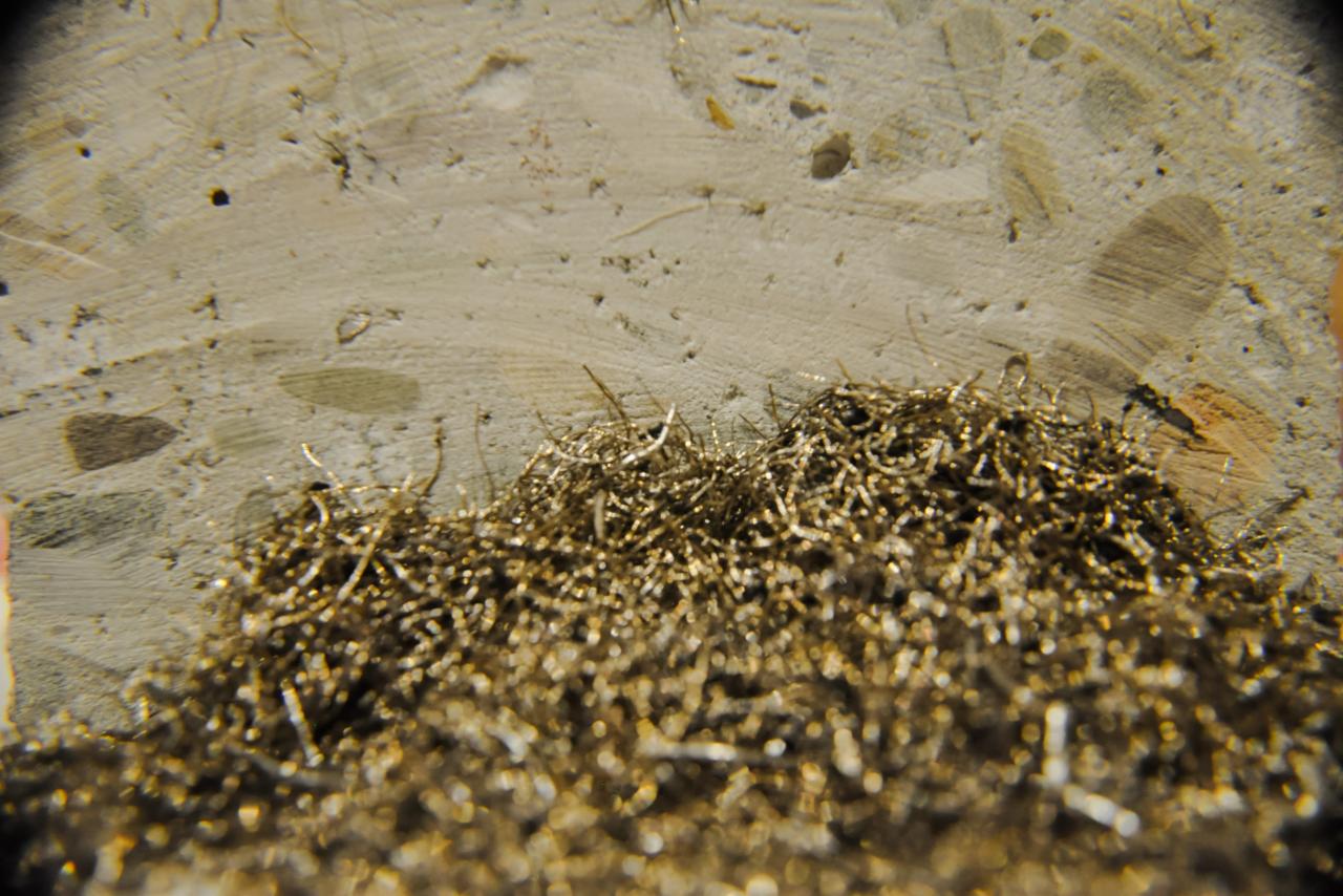 Makro zbliżenie na beton z widocznymi włóknami stalowymi, tworzącymi warstwę na powierzchni betonu.