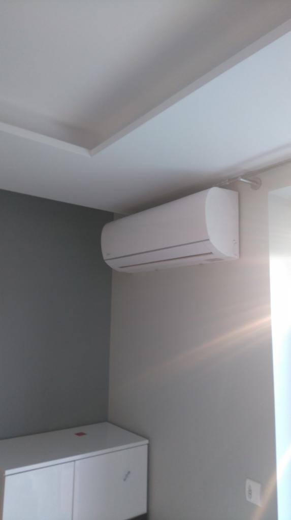 Biała jednostka wewnętrzna klimatyzacji zamontowana na szarej ścianie w pomieszczeniu w Rzeszowie, widoczny fragment sufitu z dekoracyjną listwą.