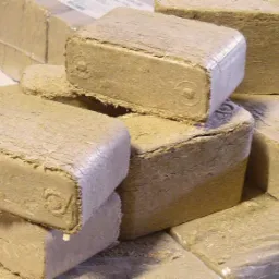 Ułożone kostki brykietu drzewnego w przezroczystej folii, widoczne charakterystyczne wgłębienia na powierzchni i krawędziach.