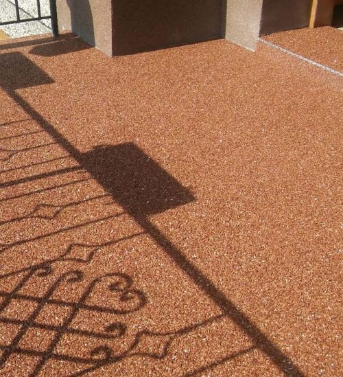 Bursztynowa, żywiczna posadzka balkonu w słoneczny dzień. Cień balustrady z motywem serca. Minimalistyczna kolumna w tle.