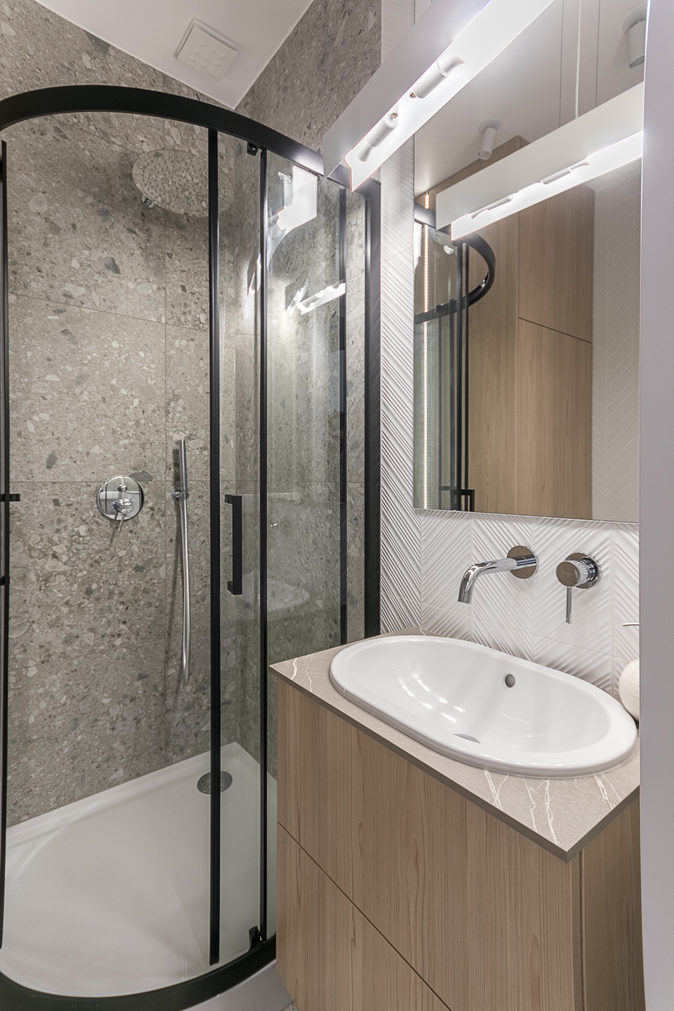 Nowoczesna łazienka z kabiną prysznicową typu walk-in, umywalką nablatową i szarą ceramiką. Minimalistyczny design, eleganckie wykończenie.