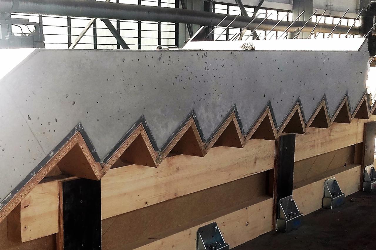 Prefabrykowany element schodów żelbetowych w drewnianej formie, widoczne metalowe elementy mocujące formę.