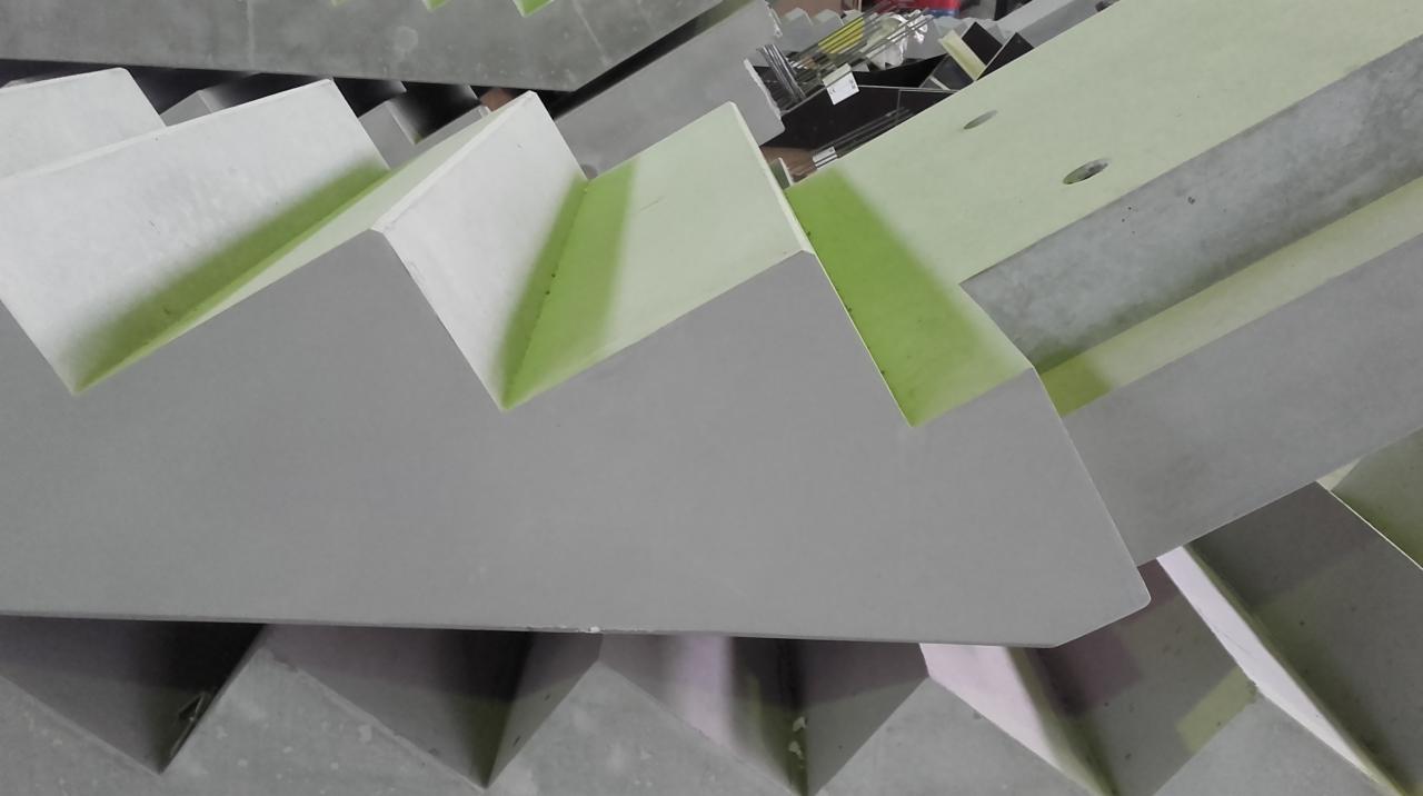 Szare, prefabrykowane betonowe stopnie schodowe ułożone jeden na drugim, widoczne ślady po formach.