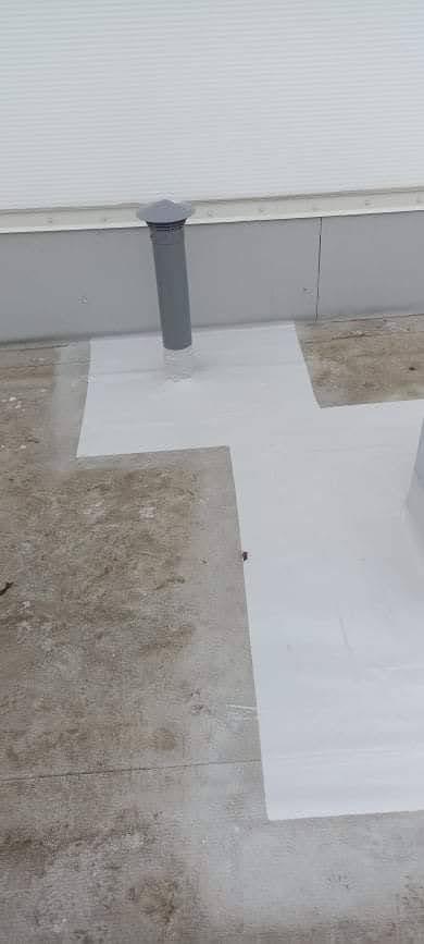 Szare, matowe wykończenie dachu z kominem wentylacyjnym, zabezpieczone białą, płynną membraną hydroizolacyjną na łączeniach.