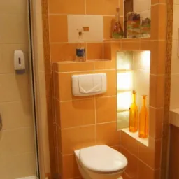 Wykończona łazienka w Hamerni z kabiną prysznicową, toaletą w zabudowie i pomarańczowymi płytkami ceramicznymi z dekoracyjnymi wnękami.