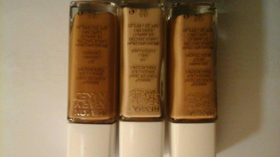 Trzy buteleczki podkładu Revlon Nearly Naked w odcieniach Caramel, Shell i Beige Tendre, ustawione obok siebie, z widocznymi etykietami i informacjami o SPF 20.
