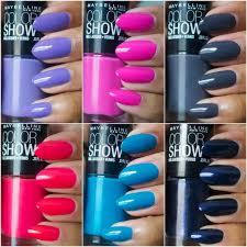 Zestawienie sześciu flakonów lakierów do paznokci marki Maybelline Color Show w różnych odcieniach (fiolet, róż, szarość, czerwień, błękit, granat), z pomalowanymi paznokciami w pasujących kolorach.