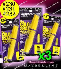 Trzy opakowania tuszu do rzęs Maybelline Volum' Express w żółtych tubkach na czarno-fioletowym tle z elementami graficznymi.