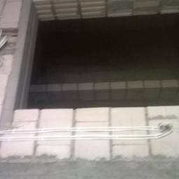 Wojciech Siwko - Białe przewody poprowadzone wzdłuż ściany z betonu komórkowego na budowie, widoczne mocowania i wiązka przewodów wychodząca ze ściany.