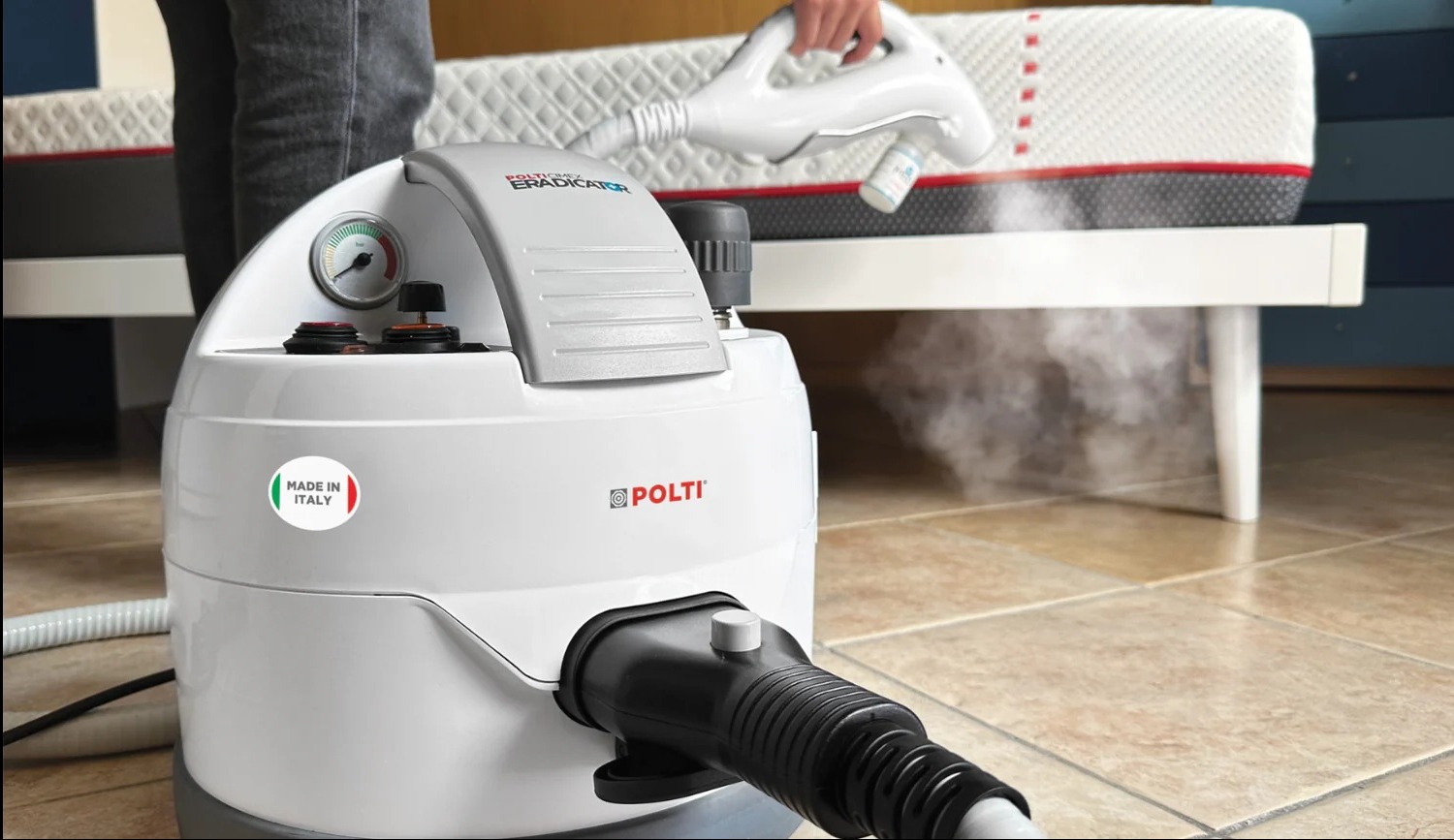 Czyszczenie parowe materaca za pomocą urządzenia Polti Eradicator, widoczna para, manometr i naklejka Made in Italy.