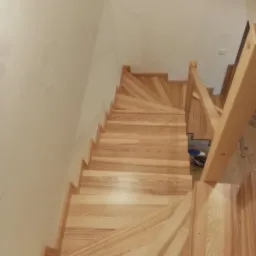 Jasne, drewniane schody z poręczą, widok z g&oacute;ry, ukazujące naturalne usłojenie drewna i minimalistyczny design.