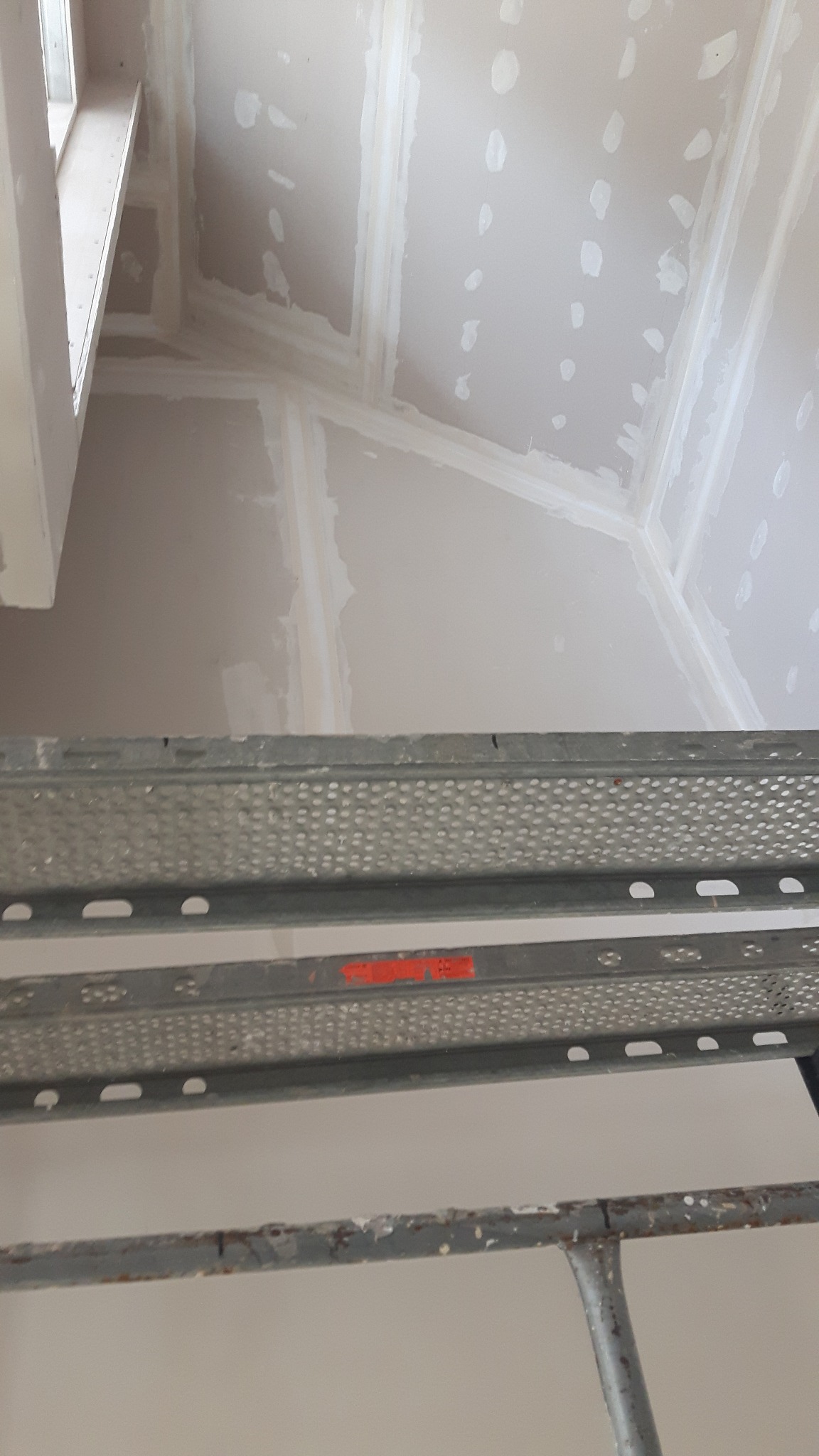 Sufit poddasza w Pobiedziskach z zamontowaną płytą, widoczne łączenia i miejsca po wkrętach przygotowane do szpachlowania, ujęcie z rusztowania.