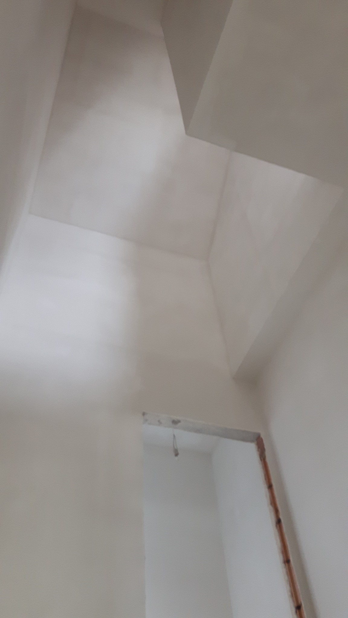 Wykończona ściana i sufit po szpachlowaniu, widoczny otwór drzwiowy z fragmentem instalacji elektrycznej w ścianie.