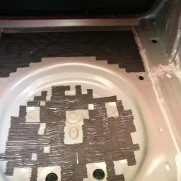 Bagażnik samochodu po nałożeniu wygłuszenia w formie pasków, widoczne niedokładności i puste przestrzenie.