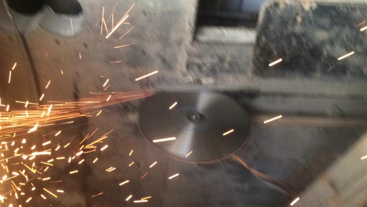 Tarcza tnąca w akcji, iskry rozbryzgują się podczas cięcia betonu, widoczne ślady pyłu.