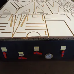 Płyta MDF z wyfrezowanymi elementami na stole roboczym frezarki CNC, widoczne detale i otwory, przygotowane do dalszej obróbki.