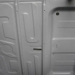 Wnętrze bagażnika samochodu po naprawach blacharskich i malowaniu na jednolity jasnoszary kolor, widoczne przetłoczenia i otwory montażowe.