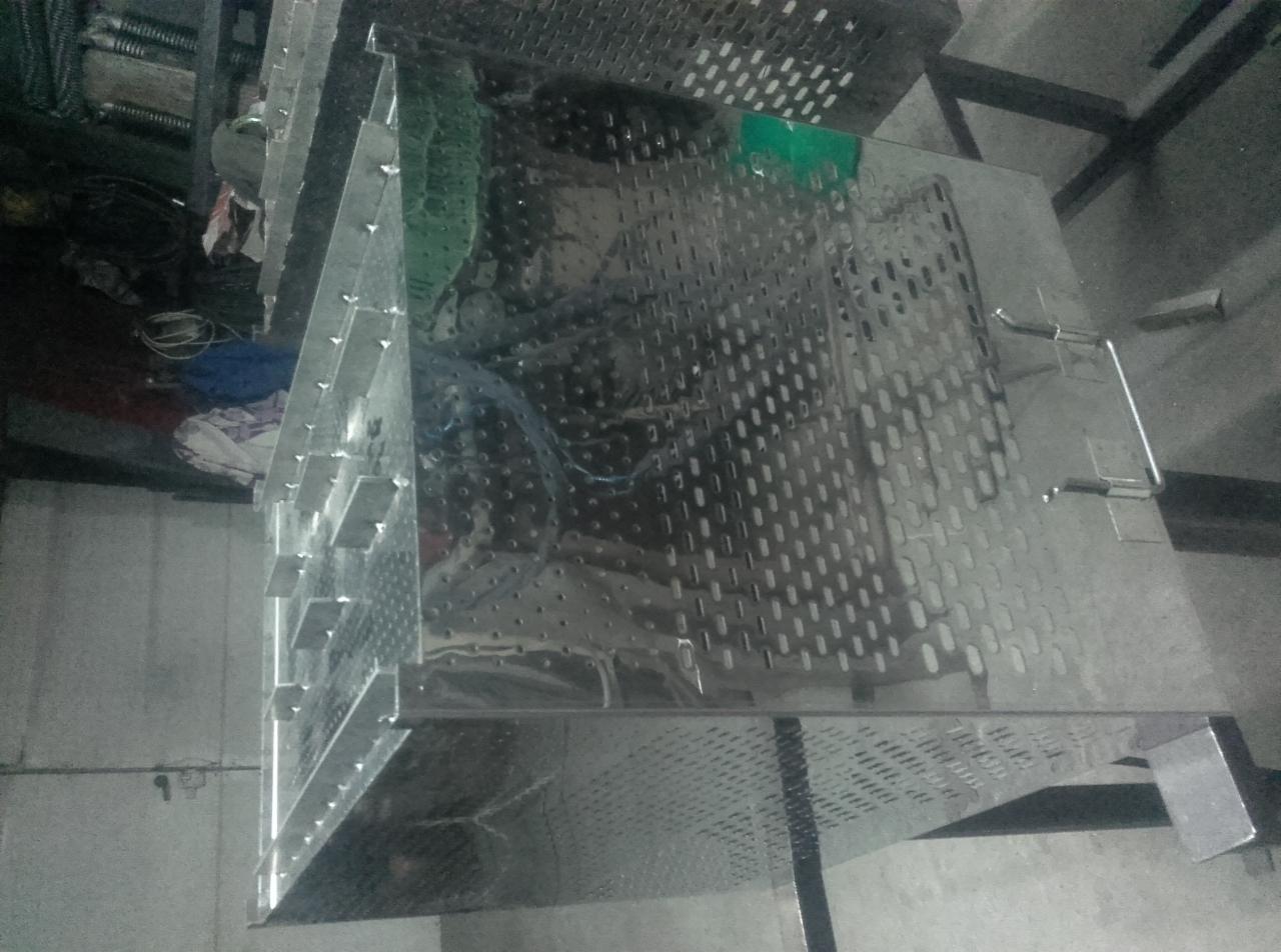 Metalowa konstrukcja z perforowanych blach, prawdopodobnie element większej całości, z widocznymi spawami i uchwytami, sfotografowana w warsztacie.