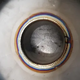 Wewnętrzny widok rury ze stali nierdzewnej po spawaniu, widoczny precyzyjny szew spawalniczy z charakterystycznymi kolorami utleniania termicznego.