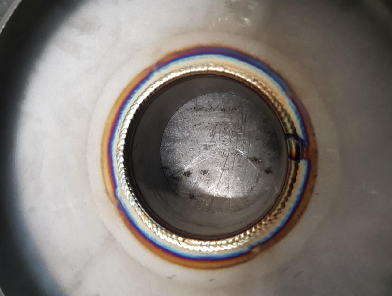 Wewnętrzny widok rury ze stali nierdzewnej po spawaniu, widoczny precyzyjny szew spawalniczy z charakterystycznymi kolorami utleniania termicznego.