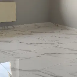 Wykończone wnętrze pokoju z białymi płytkami podłogowymi imitującymi marmur, szare ściany i zamontowany grzejnik.