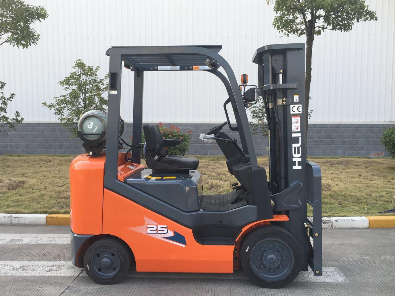Pomarańczowo-szary wózek widłowy marki HELI z butlą gazową, model 25, zaparkowany na zewnątrz, widok z boku.
