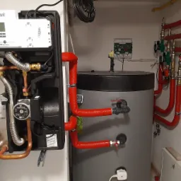 Kocioł gazowy Vaillant z pompą obiegową Grundfos, połączony z zasobnikiem ciepłej wody i instalacją centralnego ogrzewania z rurami w izolacji termicznej.