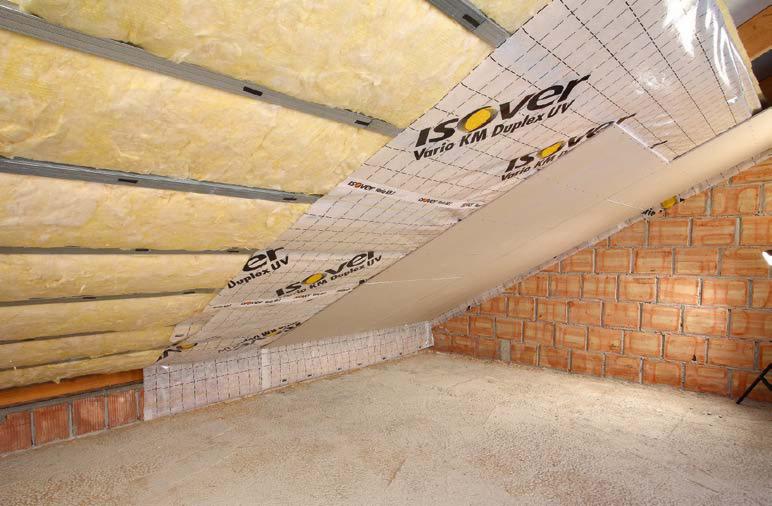 Poddasze w trakcie izolacji: wełna mineralna między krokwiami, folia paroizolacyjna Isover Vario KM Duplex UV z nadrukiem, częściowo zamontowana płyta gipsowo-kartonowa na skośnej ścianie.