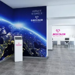 Wnętrze biura firmy z branży stolarki okiennej, z logo na ścianie i interaktywnym kioskiem informacyjnym z wyświetlaczem, na ścianie fototapeta z widokiem Ziemi nocą.