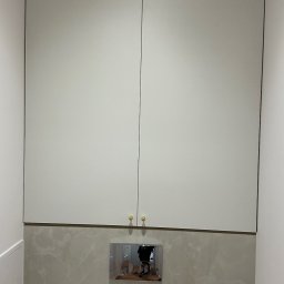 MYSTEK SPÓŁKA Z OGRANICZONĄ ODPOWIEDZIALNOŚCIĄ - Biała szafka wisząca nad stelażem WC z marmurowymi płytkami. Złote gałki dodają elegancji. Minimalistyczny design w nowoczesnej łazience.