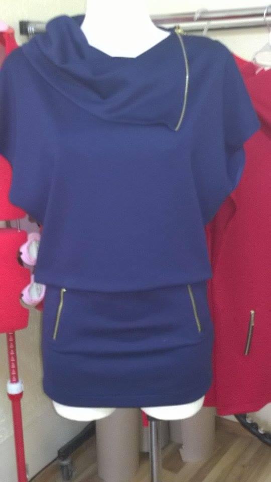 Granatowa bluza z ozdobnym zamkiem błyskawicznym na manekinie, widoczny fragment czerwonej bluzy w tle.