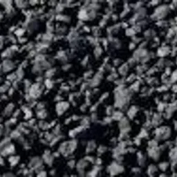 Góra czarnego, drobnego węgla kamiennego z widoczną strukturą bryłek, oświetlona ostrym światłem z góry.