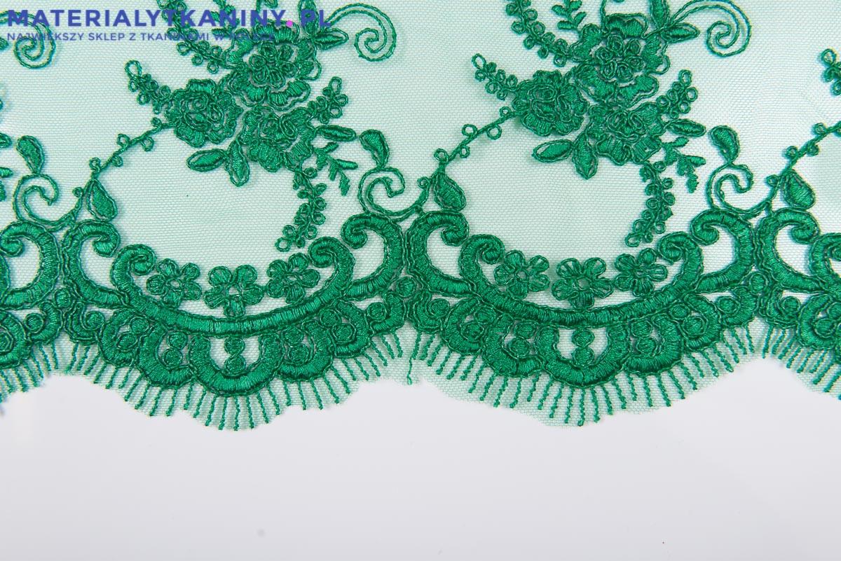 Fragment zielonej, haftowanej koronki z motywem kwiatowym na delikatnej siateczce, widoczny z bliska.