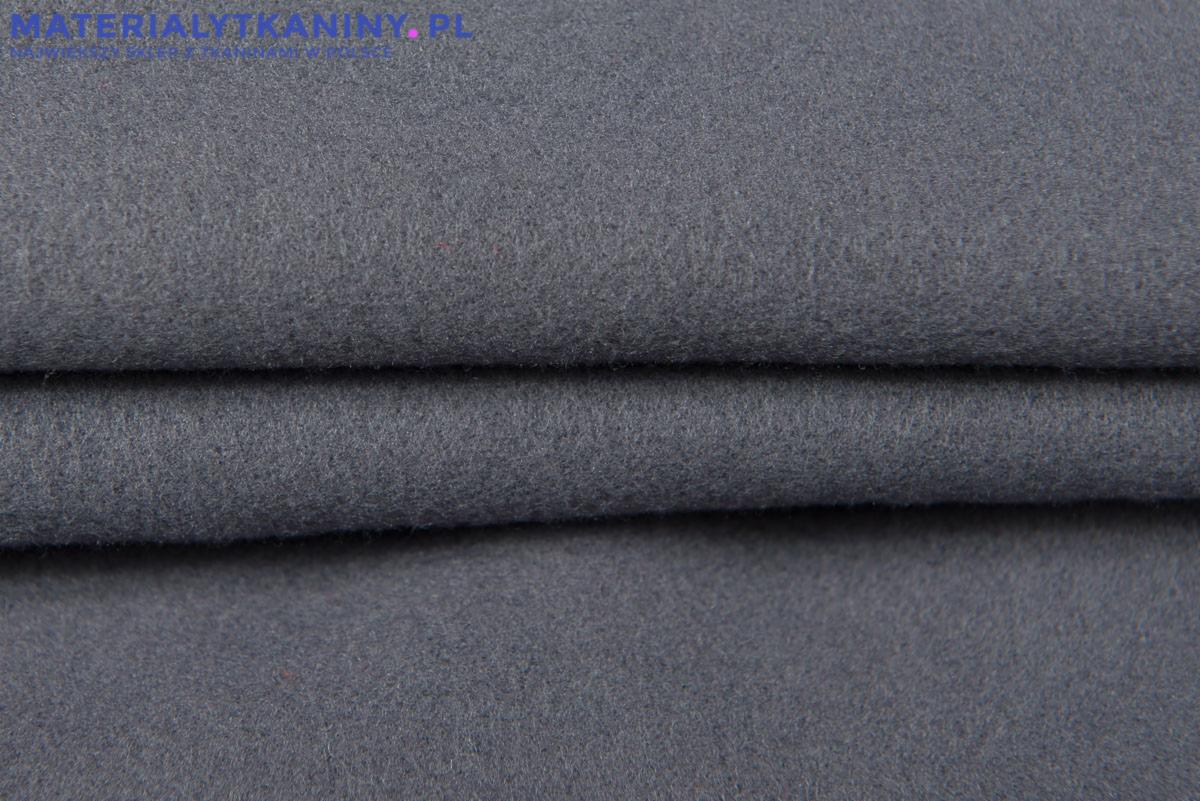 Szary, wełniany materiał złożony w fałdy, widoczna delikatna faktura włókien.
