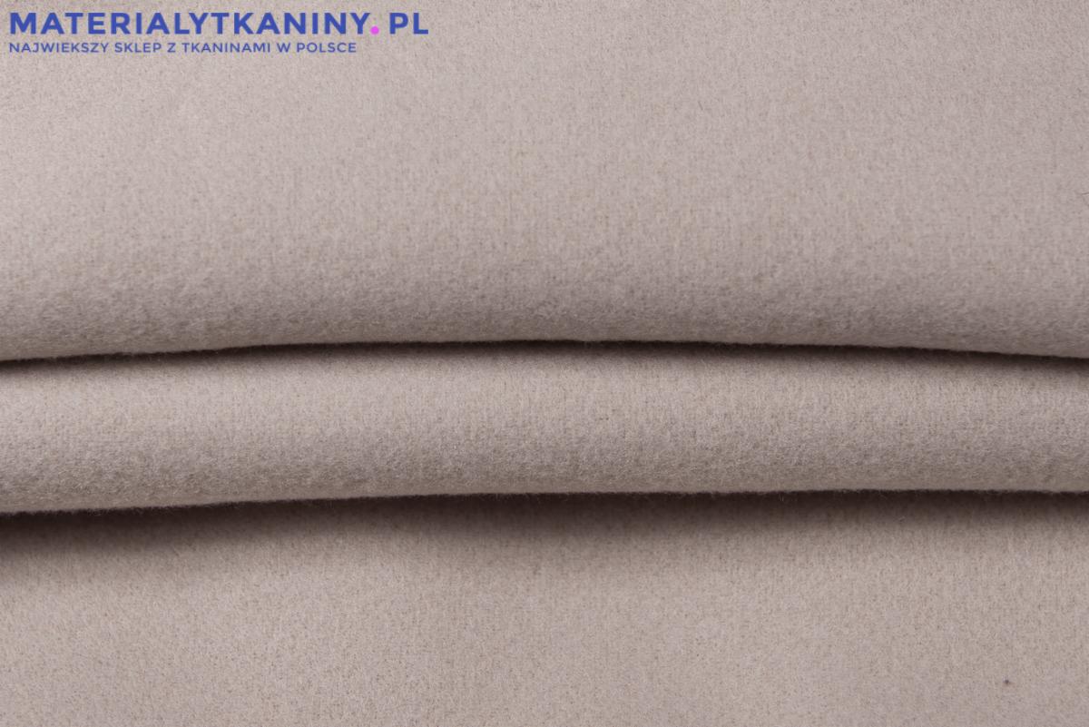 Jasnoszara, miękka tkanina wełniana, delikatnie pofałdowana, z widocznym logo sklepu internetowego w górnym lewym rogu.