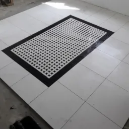 Białe płytki podłogowe z dekoracyjnym, prostokątnym wzorem wplecionym z czarno-białej mozaiki w centralnej części, ułożone w nowym pomieszczeniu.