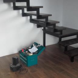 STAL-KRÓL - Montaż wspornikowych schodów drewnianych na metalowej konstrukcji, widoczna skrzynka z narzędziami i drabina.