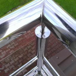 STAL-KRÓL - Kątowa, polerowana barierka ze stali nierdzewnej z widocznymi kroplami wody, zamontowana na zewnątrz, z kostką brukową i trawnikiem w tle.