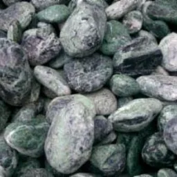 Zielone otoczaki z ciemnymi plamkami, sprzedawane w Kłobucku, ułożone w koszu z metalowej siatki.