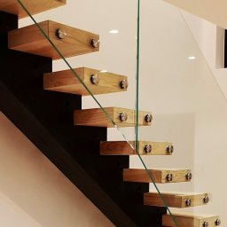 Współczesny design spotyka klasyczne piękno. Te schody na centralnej belce, wykonane z dębu, uzupełnione elegancką szklaną balustradą, dodają wnętrzu nowoczesnej lekkości.