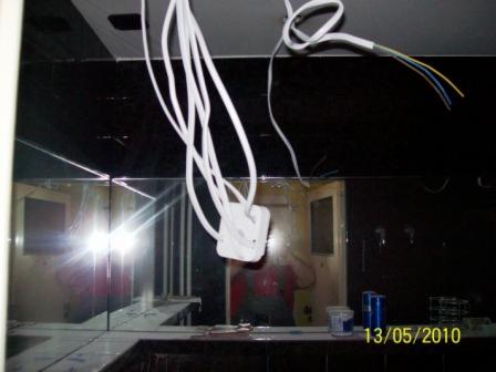 Wiszące kable elektryczne z puszką przy suficie, odbicie w lustrzanej ścianie, widoczne puszki i data na zdjęciu.