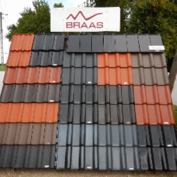 Ekspozycja dachówek Braas w różnych kolorach: pomarańczowym, brązowym i kilku odcieniach szarości, z tabliczką informacyjną 'Turmalin' na jednej z próbek.