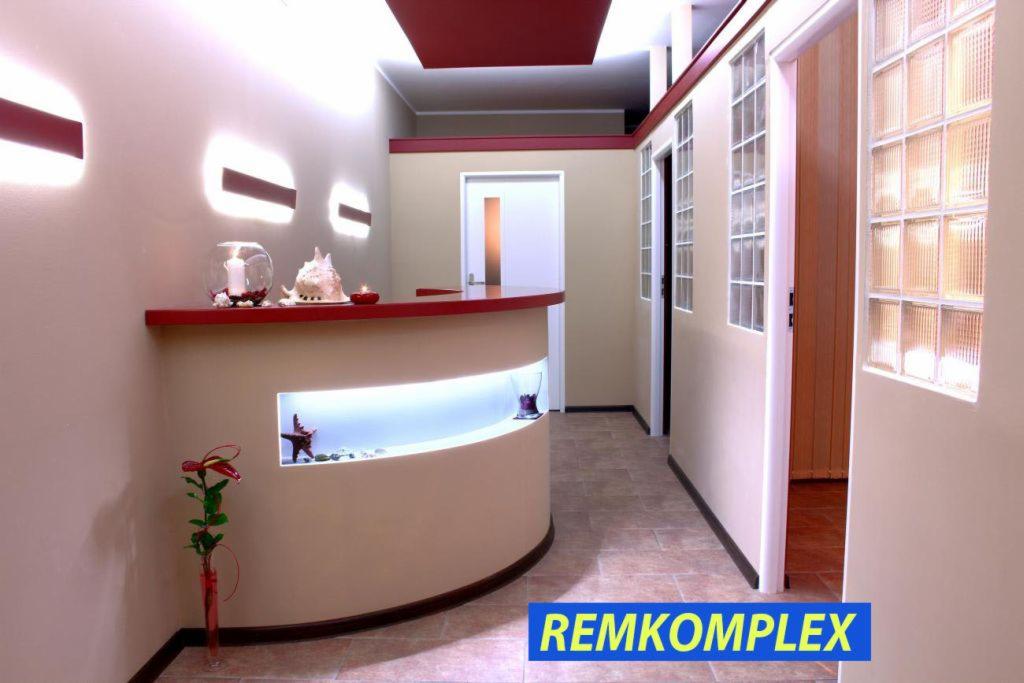 Eleganckie wnętrze z recepcją w odcieniach beżu i czerwieni, oświetlone dekoracyjnymi lampami i z elementami dekoracyjnymi, np. szklane luksfery.