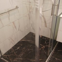 STAN -BUD - Nowoczesna kabina prysznicowa z marmurową posadzką i panelami ściennymi w odcieniach bieli i brązu. Chromowana armatura i szklane drzwi.