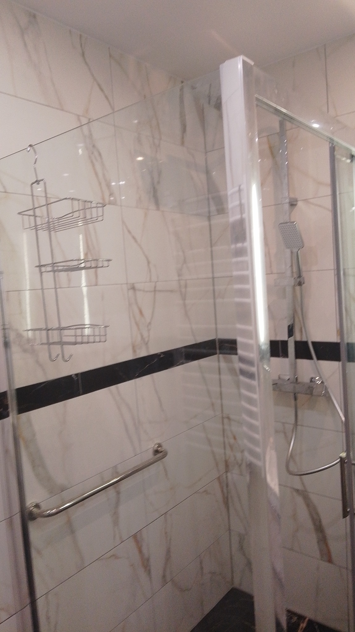 Wykończona kabina prysznicowa z marmurowymi płytkami i chromowanymi akcesoriami w Gozdowie. Nowoczesny design i funkcjonalne rozwiązania.