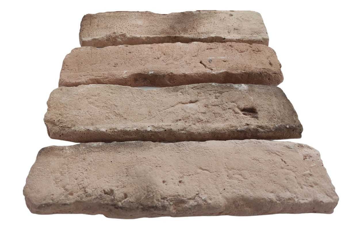 Cztery płytki ceglane klasyczne ułożone jedna na drugiej, o nieregularnej strukturze i różnej tonacji beżu i brązu, na białym tle.