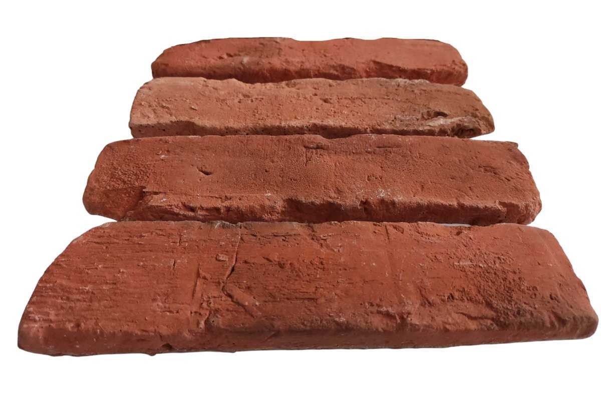 Cztery czerwone płytki ceglane ułożone jedna na drugiej, widoczne nierówności i porowata struktura.